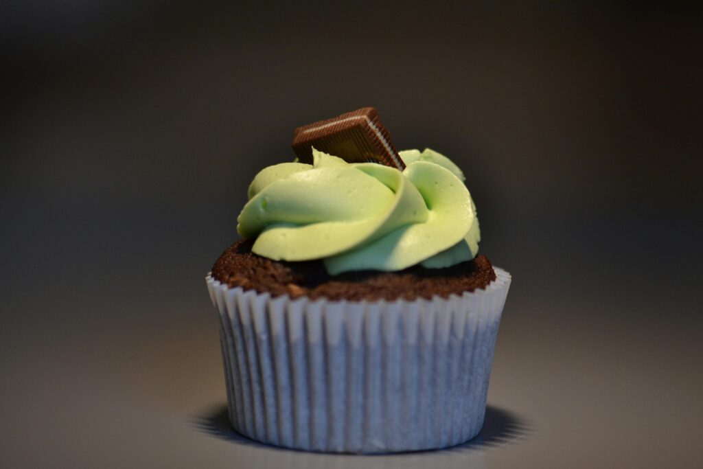 Close-up of a chocolate cupcake with mint frosting and chocolate garnish.